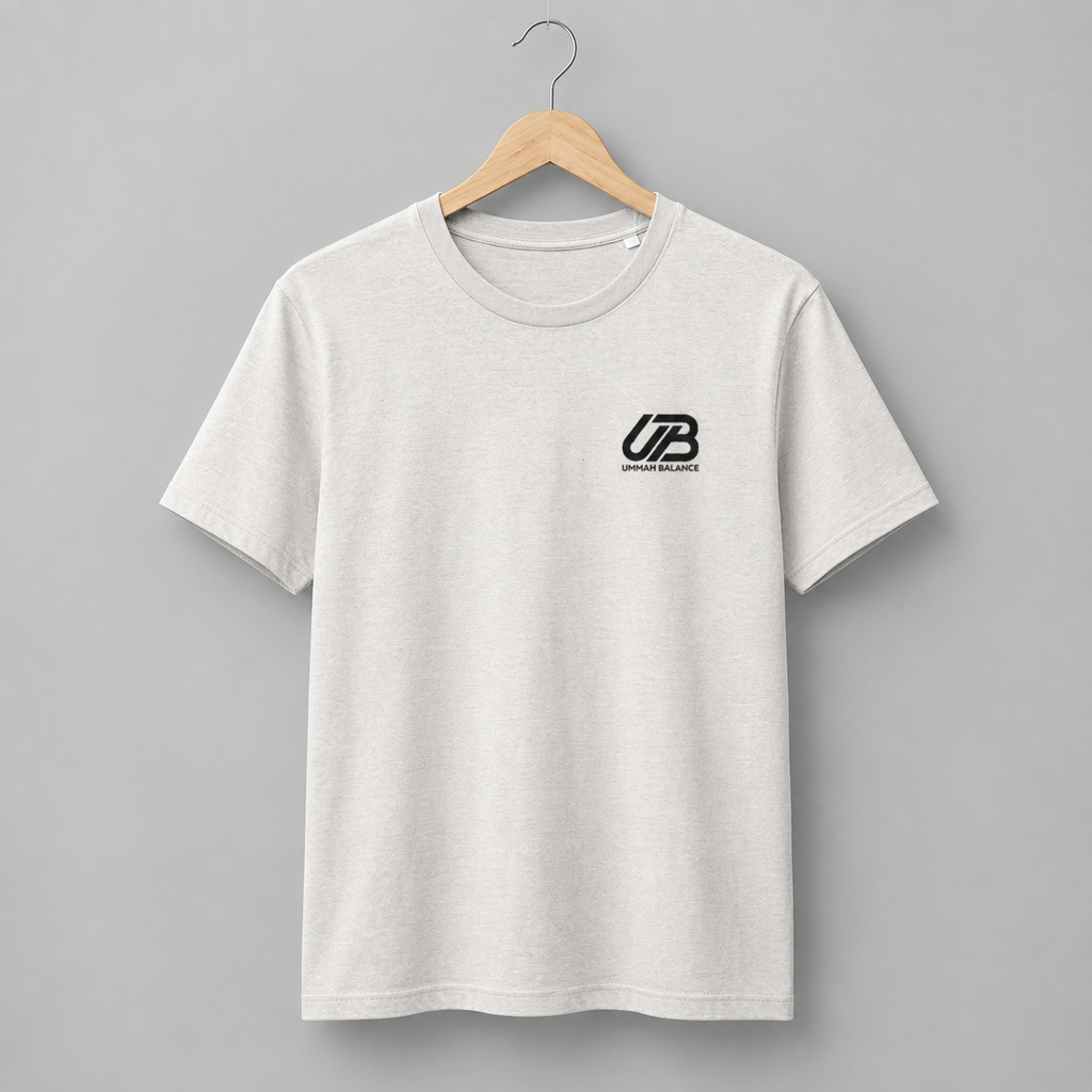 A vintage white short-sleeve crewneck t-shirt hanging on a wooden hanger. The shirt features a black small 'UB' logo on the left chest with 'Ummah Balance' printed underneath.