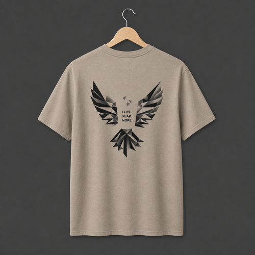 A dessert dust coloured short-sleeve t-shirt hanging on a wooden hanger. The back of the shirt features a large black abstract geometric bird graphic with the words 'LOVE. FEAR. HOPE.' in black in the middle. 