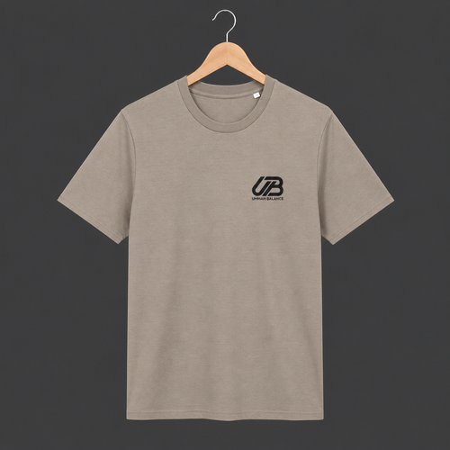 A dessert dust coloured short-sleeve crewneck t-shirt hanging on a wooden hanger. The shirt features a small black 'UB' logo on the left chest with 'Ummah Balance' printed underneath.