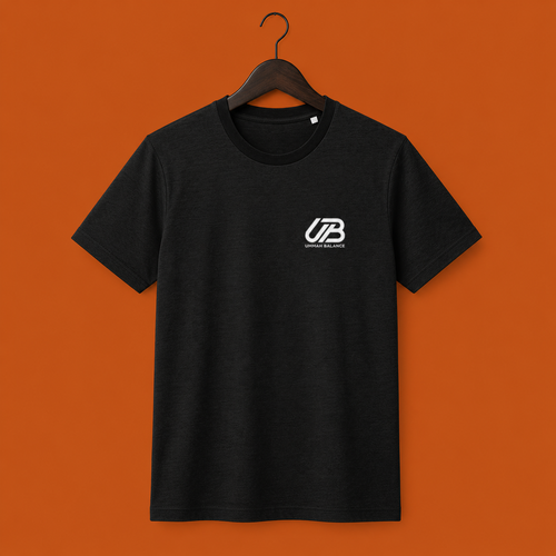 A black short-sleeve crewneck t-shirt hanging on a dark wooden hanger. The shirt features a small white 'UB' logo on the left chest with 'Ummah Balance' printed underneath.