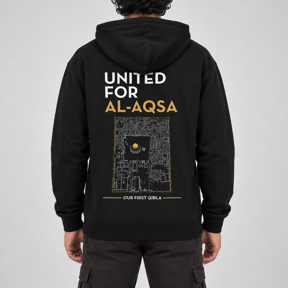 A person shown from the back wearing a black hoodie with a large graphic print on the back. The print features the text 'UNITED FOR AL-AQSA' in white and gold, a black-and-gold map design, and 'OUR FIRST QIBLA' at the bottom.